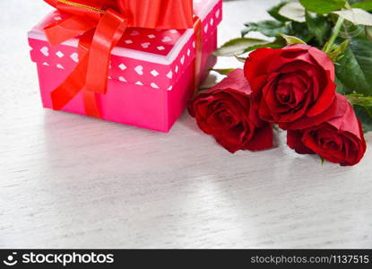 Valentines day gift box flower love concept / pink gift box with ribbon bow red roses flower on white wooden background copy space