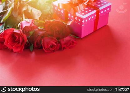 Valentines day gift box flower love concept / pink gift box with ribbon bow red roses flower on red background copy space