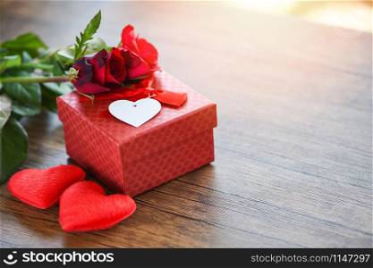 Valentines day gift box flower love concept / Red gift box with ribbon bow red roses flower and heart on wooden table rustic background