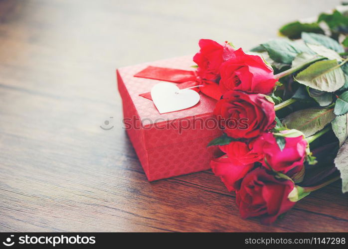 Valentines day gift box flower love concept / Red gift box with ribbon bow red roses flower on wooden table rustic background tone vintage