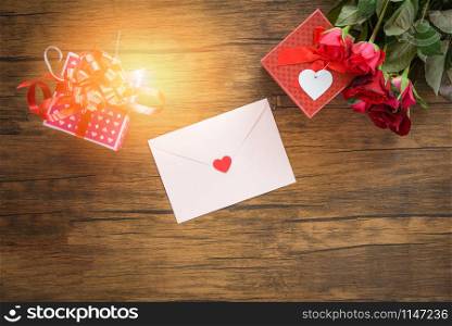 Valentines day gift box red and pink on wood background / Valentines day card red rose flower and gift box ribbon bow on wooden - Envelope love mail Valentine Letter Card with Red Heart Love concept