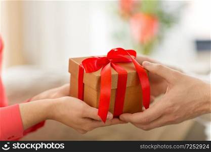 valentines day, greeting and people concept - close up of male and female hands with gift box. close up of male and female hands with gift box