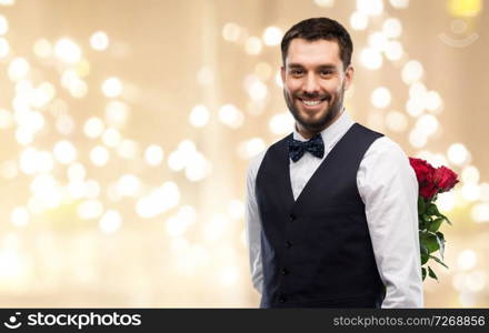 valentines day, greeting people concept - happy man in party clothes with red roses behind his back over festive lights background. happy man with red roses behind his back