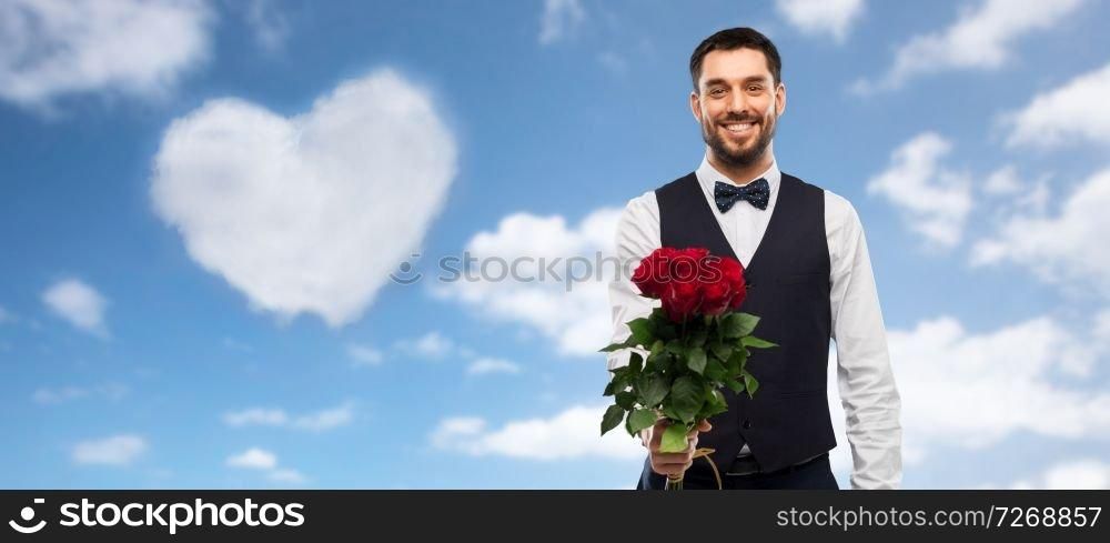valentines day, greeting people concept - happy man in party clothes with bunch of red roses over blue sky and heart shaped cloud background. happy man with bunch of red roses