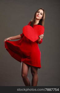 Valentines day happiness and relationships concept. Brunette woman long hair girl in red dress holding heart love symbol dancing pose dark gray background