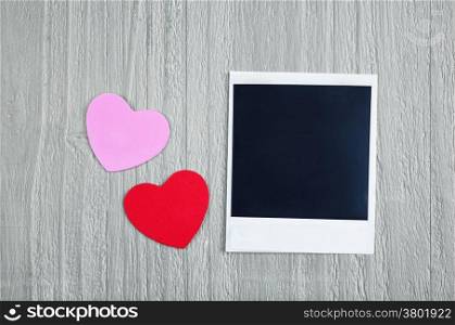 Valentines Day hearts and blank instant photo on vintage wooden background