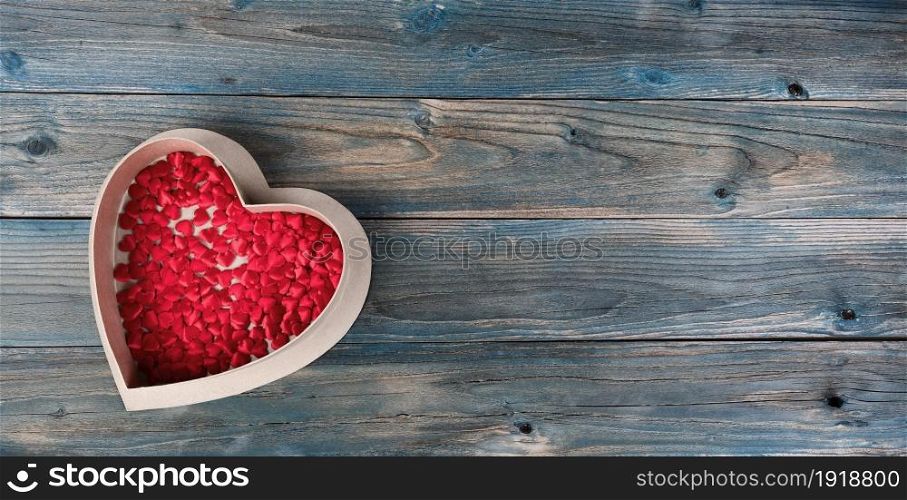 Valentines day holiday background with gift box filled little heart shapes on faded blue wooden planks