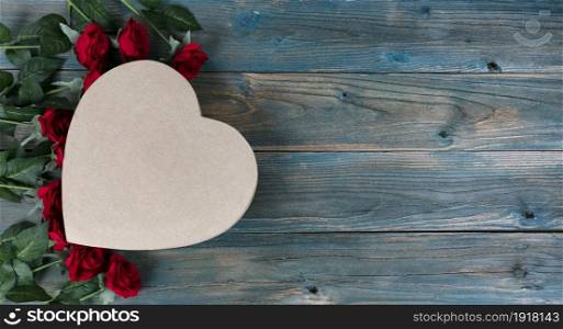 Valentines day holiday background with lovely red roses and heart shaped gift box on faded blue wooden planks