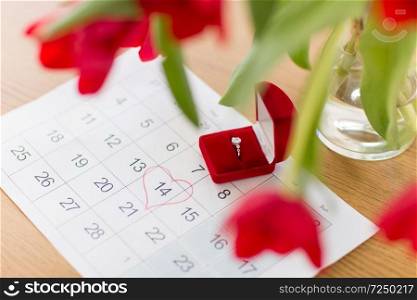 valentines day, jewelry and holidays concept - diamond ring in red velvet gift box and calendar sheet with 14th february date marked by heart shape. diamond ring and calendar sheet on valentines day