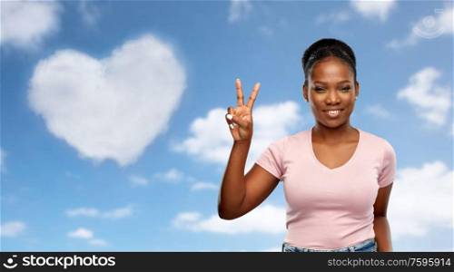 valentines day, love and gesture concept - happy african american young woman showing peace hand sign over pink background. happy african american woman showing peace