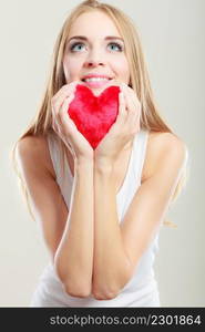 Valentines day love and relationships concept. Blonde long hair young woman holding red heart love symbol studio shot on gray