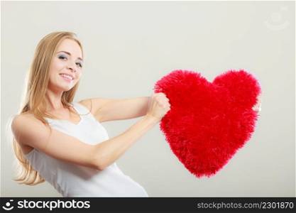 Valentines day love and relationships concept. Blonde long hair young woman holding heart shaped pillow love symbol