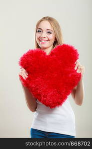 Valentines day love and relationships concept. Blonde long hair young woman holding heart shaped pillow love symbol