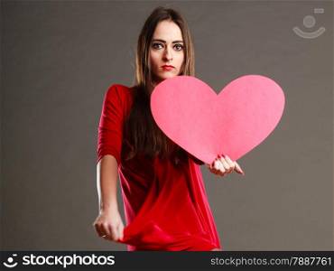 Valentines day love and relationships concept. Brunette woman long hair girl in red outfit holding heart love symbol dark gray background