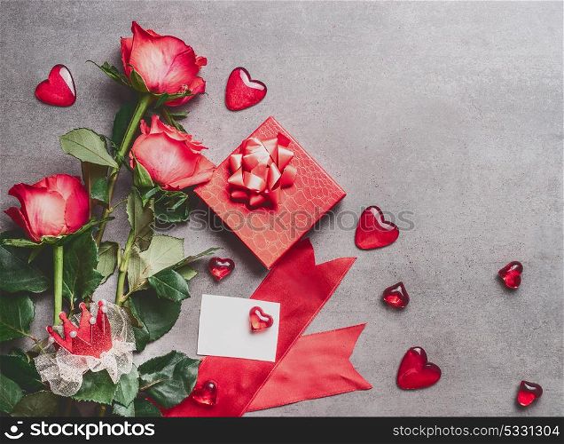 Valentines day, love or dating concept. Red roses bunch with gift box, blank paper greeting card and hearts , top view, mock up