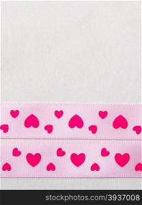 Valentines day or wedding concept. Pink heart satin ribbon on abstract white cloth background, copy space. Border design