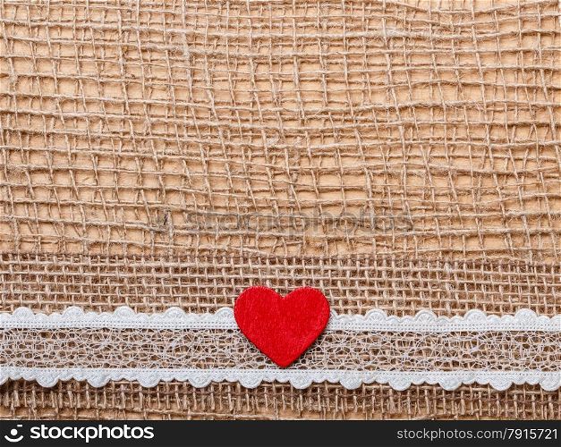 Valentines day or wedding concept. Red wooden decorative heart lace ribbon on abstract cloth burlap background with copy space