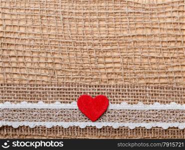 Valentines day or wedding concept. Red wooden decorative heart lace ribbon on abstract cloth burlap background with copy space