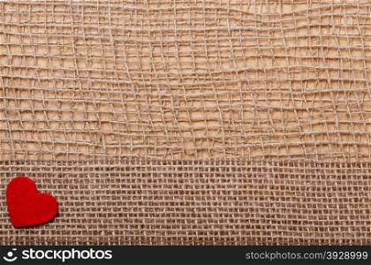 Valentines day or wedding concept. Red wooden decorative heart sacking ribbon on abstract cloth burlap background with copy space