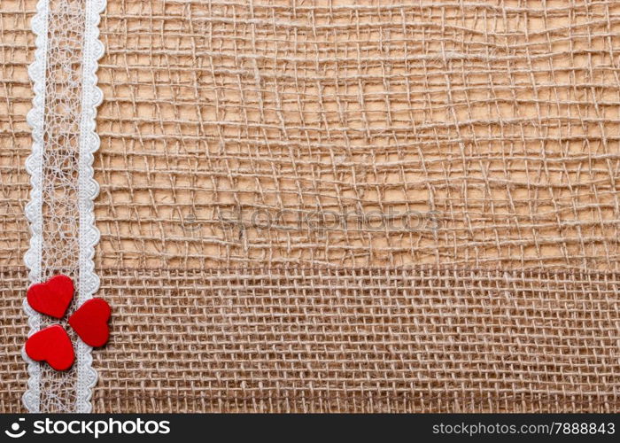 Valentines day or wedding concept. Red wooden decorative hearts lace ribbon on abstract cloth burlap background with copy space