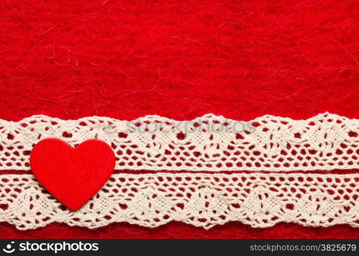 Valentines day or wedding concept. Wooden decorative heart lace ribbon on abstract red cloth background. Border frame.