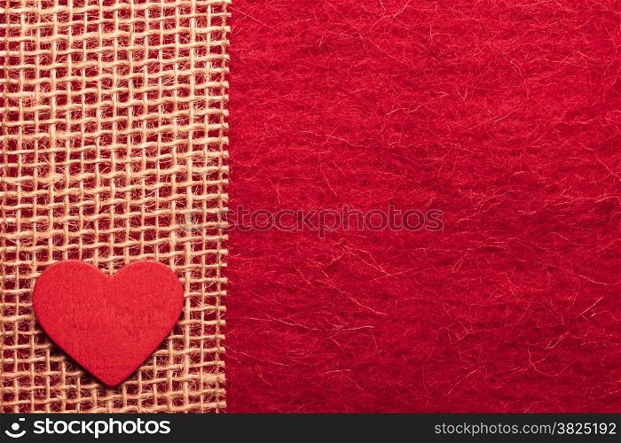 Valentines day or wedding concept. Wooden decorative heart sacking ribbon on abstract red cloth background. Border frame.