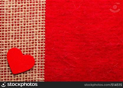 Valentines day or wedding concept. Wooden decorative heart sacking ribbon on abstract red cloth background. Border frame.