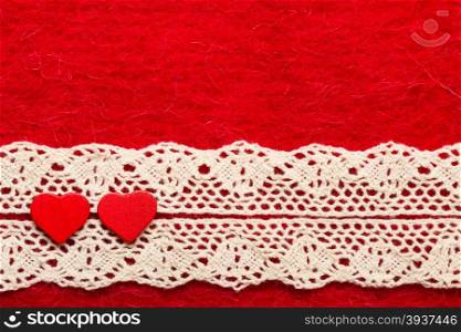 Valentines day or wedding concept. Wooden decorative hearts lace ribbon on abstract red cloth background. Border frame.