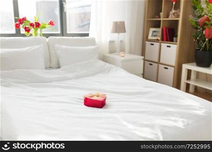 valentines day, romantic date and holidays concept - gift in shape of heart on bed at home bedroom . heart shaped gift box on bed at home bedroom 
