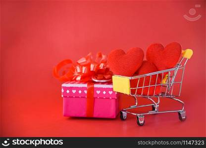 Valentines day shopping and Gift Box love concept / Pink present box with ribbon bow and Red Heart in shopping cart gift box on red background for valentines day