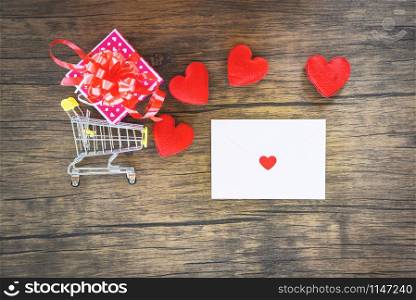 Valentines day shopping and red heart gift box on shopping cart and Envelope love mail Valentine Letter Card / Shopping holiday for Valentines day on wooden background - Shopping vacation