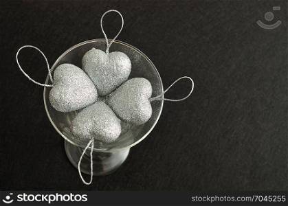 Valentines day. Silver hearts in a glass isolated against a black background. Top view.