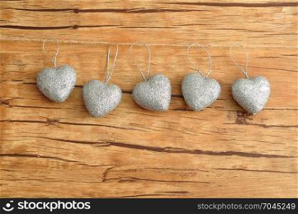 Valentines day. Six silver hearts isolated against a wooden background