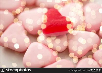 valentines day, sweets and confectionery concept - close up of red and pink heart shaped candies over festive lights. close up of red and pink heart shaped candies