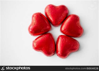 valentines day, sweets and confectionery concept - close up of red heart shaped chocolate candies on white background. close up of red heart shaped chocolate candies