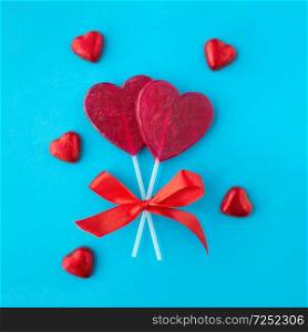 valentines day, sweets and romantic concept - red heart shaped lollipops on blue background. red heart shaped lollipops for valentines day