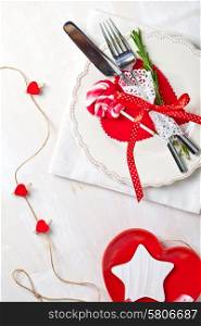 Valentines day table setting with plate, knife, fork, red ribbon and hearts