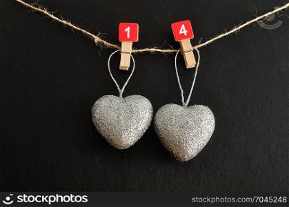 Valentines day. Two silver hearts hanging on a rope with the numbers 1 and 4 to symbolize the fourteen of February