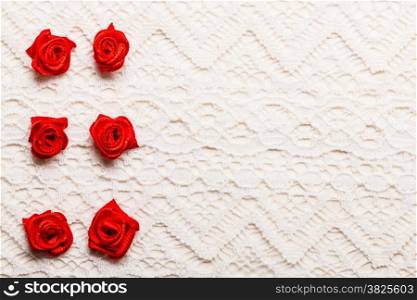 Valentines day wedding, invitation or greeting card. Red decorative satin rose flowers on white cloth lace background