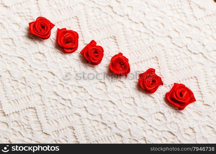 Valentines day wedding, invitation or greeting card. Red decorative satin rose flowers on white cloth lace background