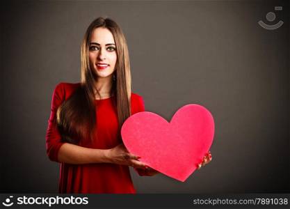 Valentines Day. Woman holding heart sign with copy space on grey background in studio.