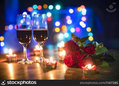 Valentines dinner romantic love concept / Romantic table setting decorated with couple champagne glass wine and roses flower with candlelight on wooden table dinner colorful light bokeh background