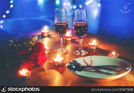 Valentines dinner romantic love concept / Romantic table setting decorated with Red heart fork spoon on plate and couple champagne glass wine roses with candlelight on wooden table dinner at night