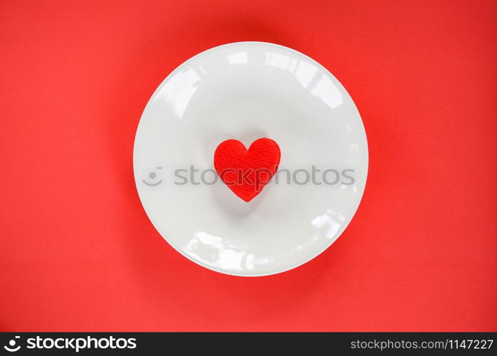 Valentines dinner romantic love food and love cooking concept / Red heart on white plate romantic table setting decorated on red texture background top view