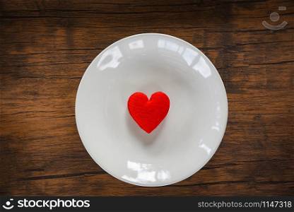 Valentines dinner romantic love food and love cooking concept / Red heart on white plate romantic table setting decorated with red heart wooden rustic texture background