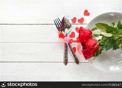Valentines dinner romantic love food and love cooking concept - Romantic table setting decorated with fork spoon and rose on plate white wooden texture background top view copy space