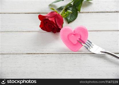 Valentines dinner romantic love food and love cooking concept - Romantic table setting decorated with red rose flower pink heart on fork white wooden texture background