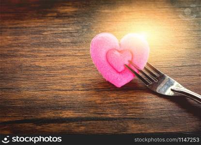 Valentines dinner romantic love food and love cooking concept - Romantic table setting decorated with fork and pink heart on wooden rustic texture background