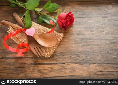 Valentines dinner romantic love food and love cooking concept - Romantic table setting decorated with wooden fork spoon roses flower on rustic wooden background