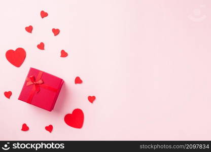 Valentines&rsquo; day background. Red gift box with ribbon bow and wood red hearts shaped composition greeting card for love isolated on pink background with copy space. Top View from above